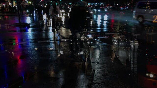 Composite video of traffic in rainy evening city with lights reflecting in the streets. Cars and bicycles with headlights and lights on in night city. 