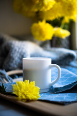 Black coffee in white mug with elegant blue napkin and yellow flowers