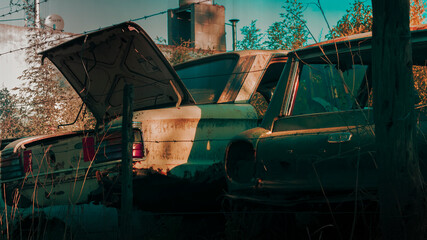 Old rusty car parked on a junkyard under sunlight