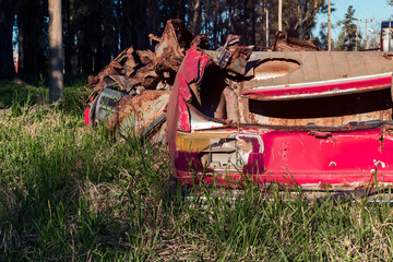 Close-up of the back of an old red car abandoned and completely destroyed