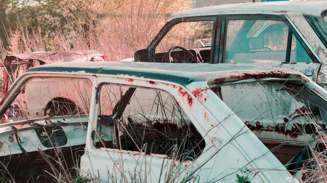 Close-up of a pair of completely destroyed cars abandoned on a junkyard outdoors