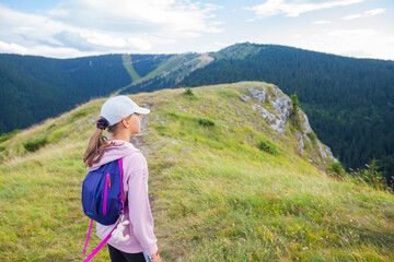 Little girl with backpack admire amazing view, beautiful summer mountain nature landscape.  Children activity