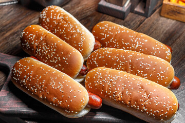 Hot dogs sprinkled with sesame seeds on a cutting board.