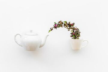 Tea concept with white teapot and dry tea leaves