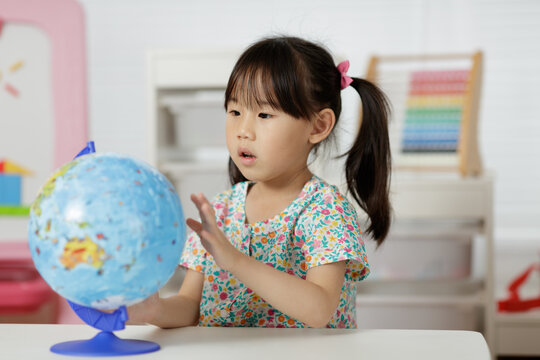 young girl learning world globe at home