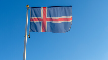 Iceland flag is on blue sky background. Flag of Iceland waving in the wind against the sky. Diplomacy concept.