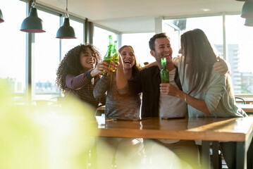 Smiling colleagues toasting drink bottles in office