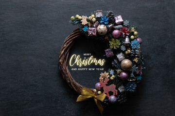 Merry Christmas text with wreath and colored decor on black background. Minimalistic design greeting card