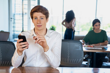 Portrait of young man using smart phone in office