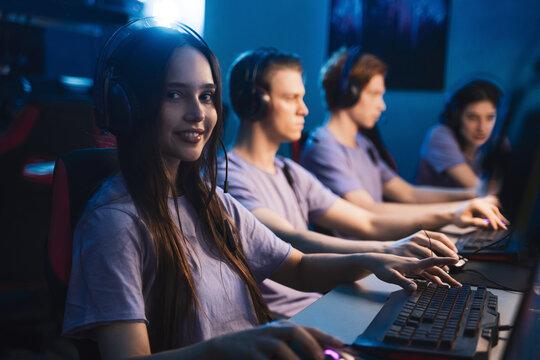 Woman wearing headset looking at the camera while playing at the computer games