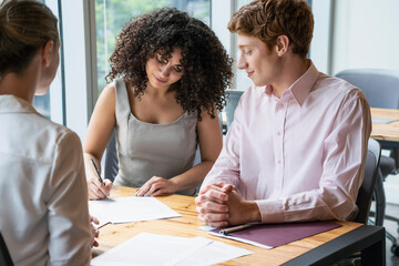 Young couple signing contract in office