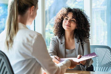 Mature woman delivering a document to young woman in office