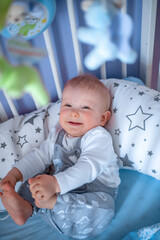 cute baby lies in a crib and smiles.