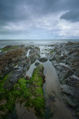Cullenstown Beach, Wexford, Ireland. Spectacular foreground full of very powerful rocks with beautiful lines of water that surround it. Very cloudy sky with slight light vents.