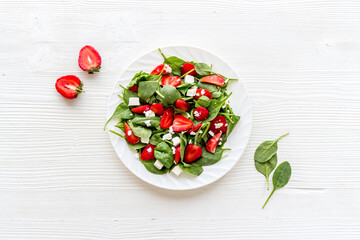 Fresh vegetarian green salad with strawberries and cheese, top view