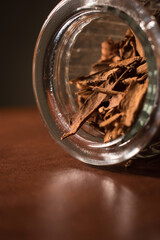 Cinnamon sticks in a glass pot on a brown table 