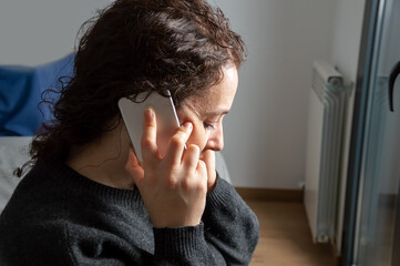 Fototapeta premium Close-up of Serious woman attending a phone call sitting on a bed in the bedroom