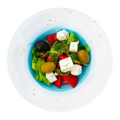 Greek salad with fresh vegetables and feta cheese on a ceramic plate. Isolated over white background