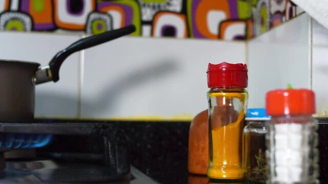 Hand putting a cooking spices pot on a kitchen meson in a kitchen at home 