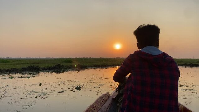 Silhoutte of a lonely man sailing in a boat and looking towards the sun. Pov shot in 4k.