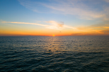 Fototapeta premium Aerial view Beautiful view sunset over sea surface beautiful wave Amazing light sunset or sunrise sky over sea beach with wave crashing on sandy shore