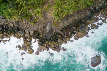 Aerial top view of sea waves crashing on rocks with coconut palm trees Beautiful seashore in Phuket Thailand Amazing nature seascape