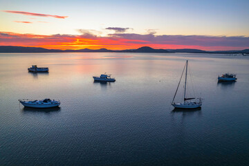 Fototapeta premium Pink and purple sunrise waterscape with boats