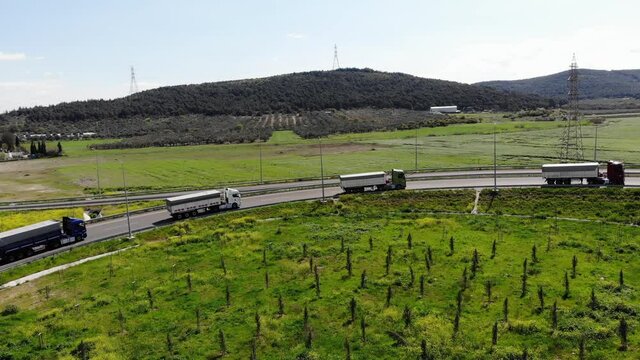 on-road trucks. Convoy of trucks ride on the highway, road junction near forest, logistic transportation, view of the road from height. trucks are on their way for export. logistics trucks