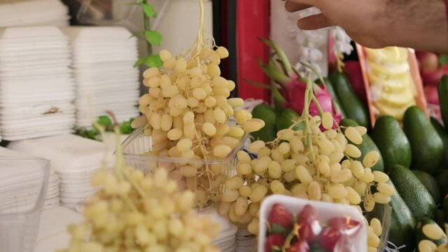 greengrocer puts grapes on the shelf. grapes ready for sale. green grapes at the grocery counter