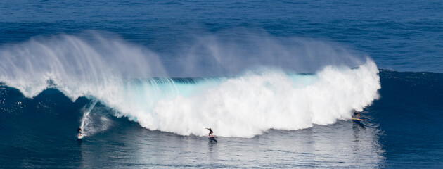Surfing giant waves in the blue water of Maui Hawaii