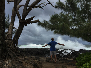 Man meditating watching giant waves on the coastline of Maui Hawaii