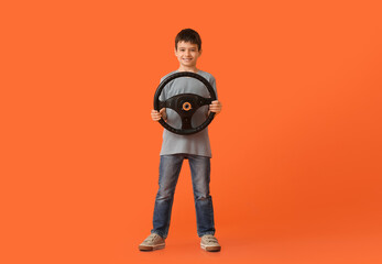 Fototapeta premium Little boy with steering wheel on color background
