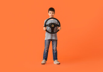 Little boy with steering wheel on color background