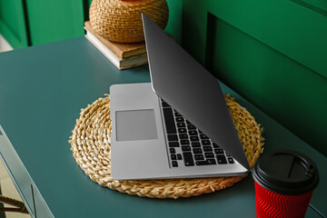 Stylish workplace with laptop near green wall