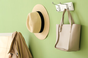 Hat and bag hanging on green wall in hallway