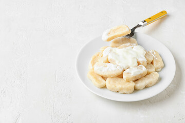 Plate with delicious dumplings and sauce on light background