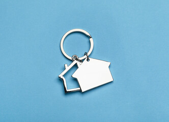 Silver house shaped keychain with keyring on blue background