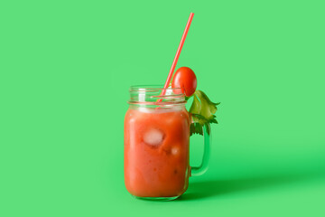 Mason jar of bloody mary with straw on color background