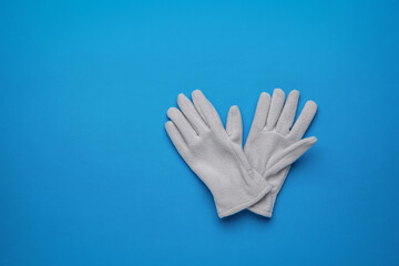 Obraz premium A pair of women's sports-style fleece gloves on a blue background. Flat lay.