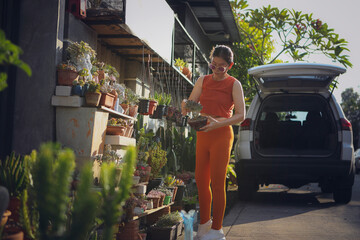 Obraz premium beautiful woman holding succulent pot in hand standing at home garden