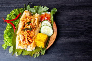 Nasi Bakar, Indonesian traditional food, filled with sliced chicken, decorated with cucumber, fried tofu, and chili sauce
