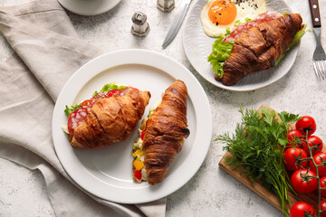 Plates with delicious croissant sandwiches on light background