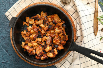 Frying pan with tasty cracklings on black background