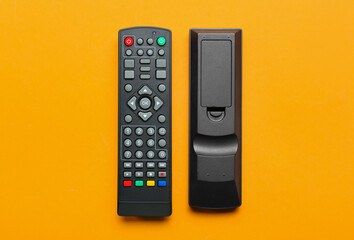 Modern TV remote controllers on orange background