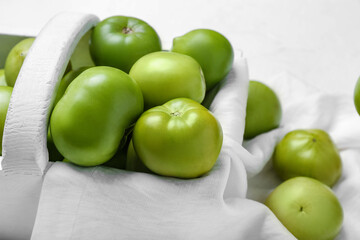 Wooden basket with fresh green tomatoes on white background, closeup