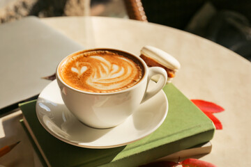 Cup of tasty coffee and books on table in cafe