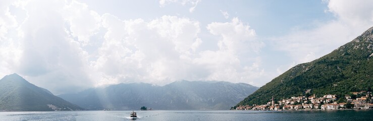 Fototapeta na wymiar Motor boat sails past the coast of Perast. Montenegro. Panorama