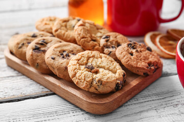 Board of tasty homemade cookies with chocolate chips on white wooden background