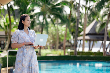 Asian woman using a laptop at the pool