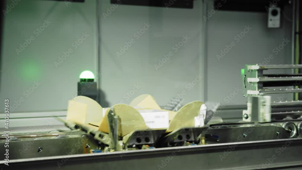 Poster packages on assembly line being boxed through an automated packaging machine